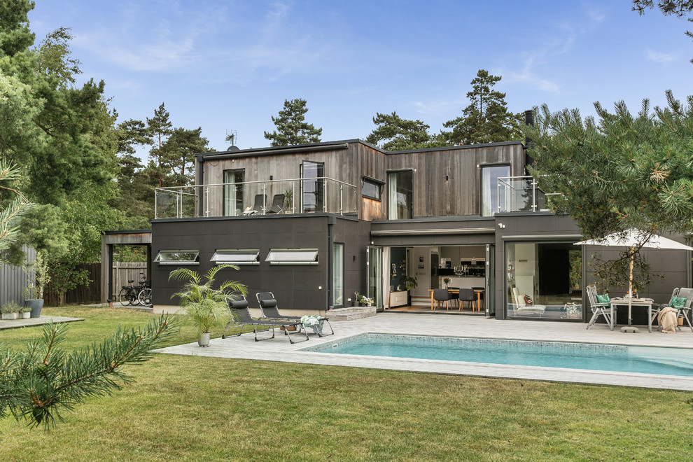 Cette image montre une façade de maison grise design à un étage avec un revêtement mixte et un toit plat.