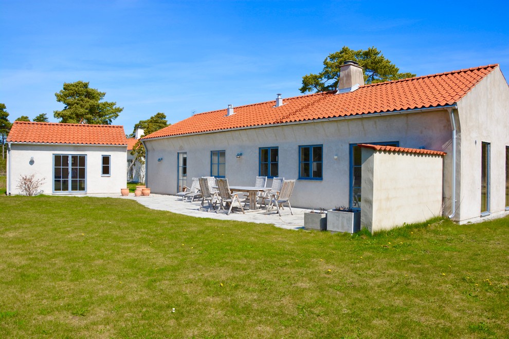Cette photo montre une petite façade de maison blanche nature de plain-pied avec un toit à deux pans et un toit en tuile.