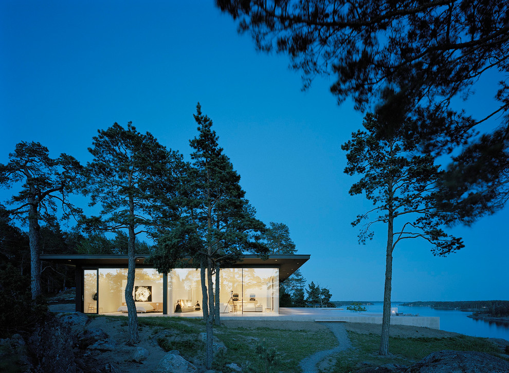 На фото: одноэтажный, стеклянный дом среднего размера в стиле модернизм с плоской крышей с