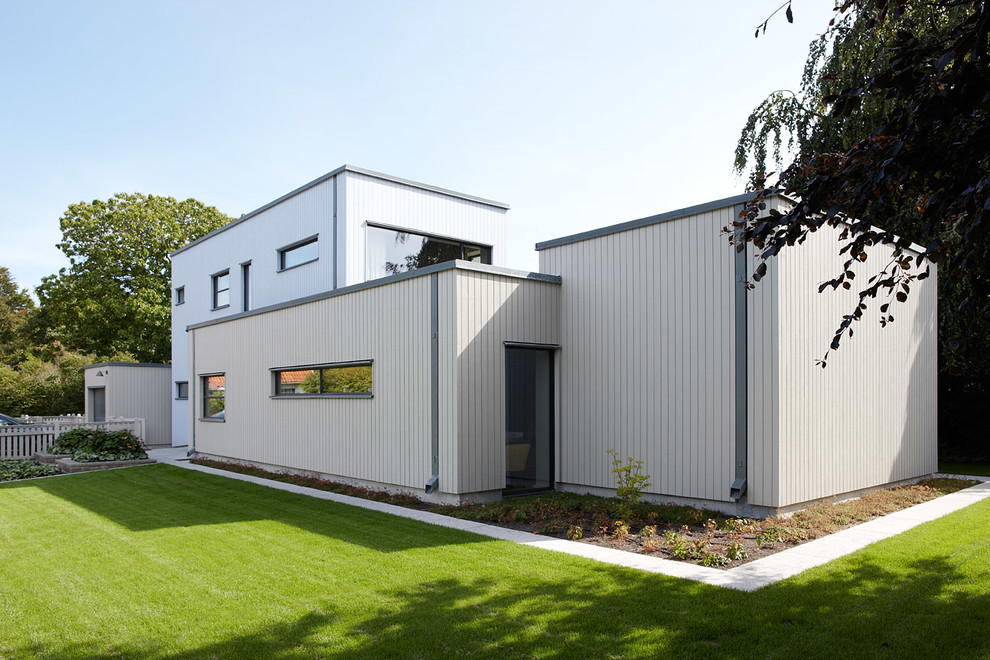 This is an example of a medium sized and gey contemporary two floor house exterior in Malmo with wood cladding and a flat roof.