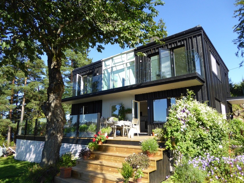 Réalisation d'une façade de maison noire minimaliste en bois de taille moyenne et à un étage.