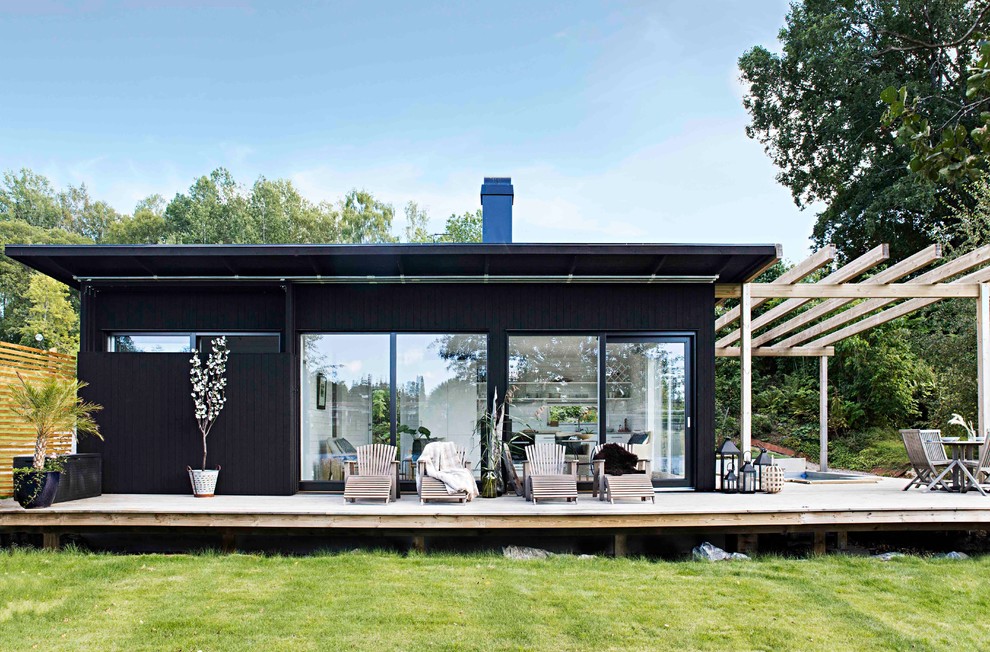 Diseño de fachada negra escandinava grande de una planta con revestimiento de madera y tejado plano