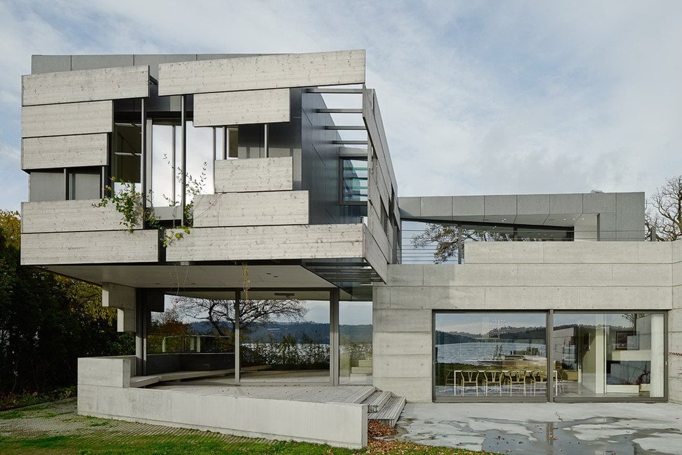 Стильный дизайн: двухэтажный, серый, большой дом в современном стиле с облицовкой из бетона и плоской крышей - последний тренд