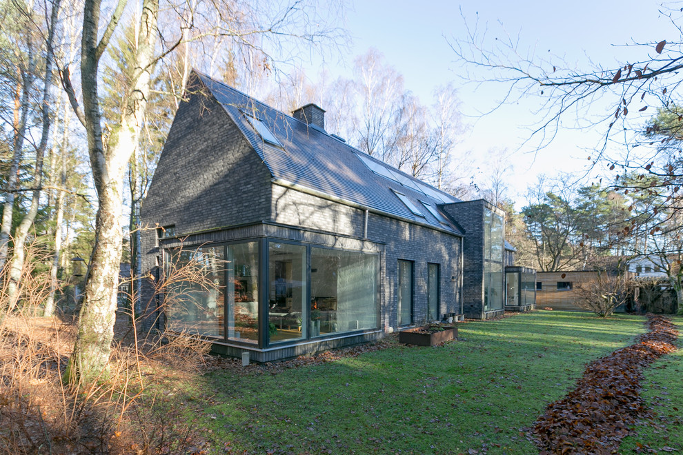 Cette image montre une façade de maison noire nordique en brique à un étage.