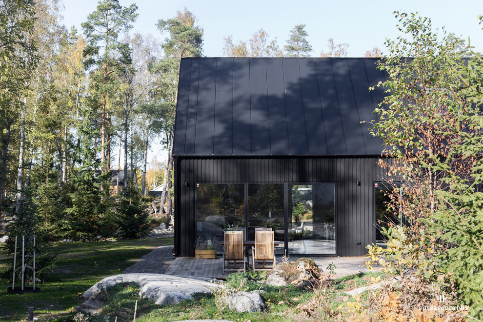 Cette image montre une façade de maison noire nordique en bois de taille moyenne et de plain-pied avec un toit à deux pans.