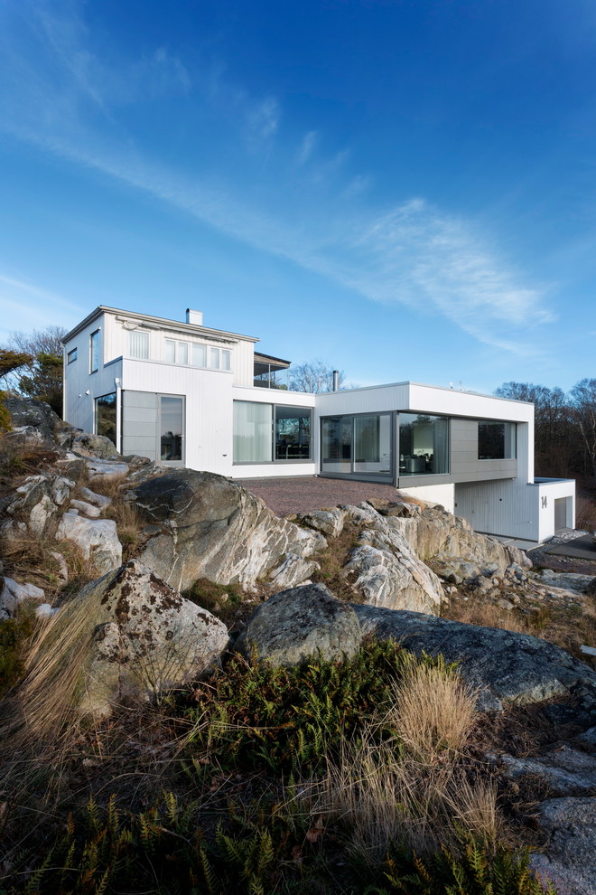 Exemple d'une très grande façade de maison blanche scandinave en pierre à deux étages et plus avec un toit plat.