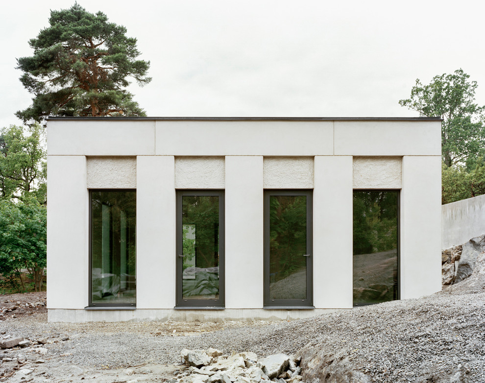 Inspiration pour une façade de maison blanche minimaliste en pierre de taille moyenne et à un étage avec un toit plat.