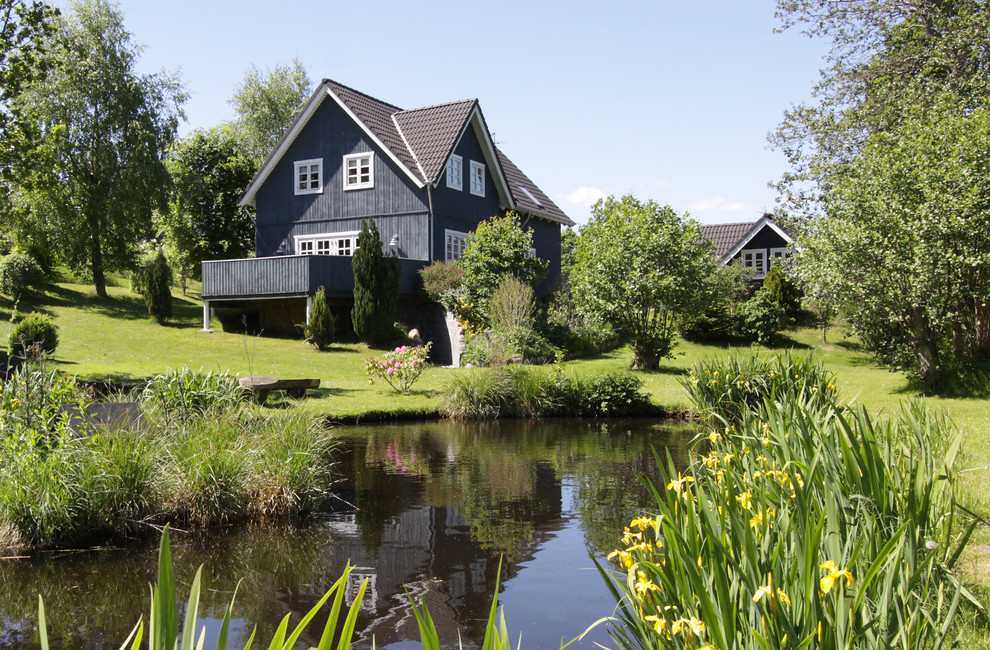 Стильный дизайн: двухэтажный, деревянный, черный дом среднего размера в скандинавском стиле с двускатной крышей - последний тренд