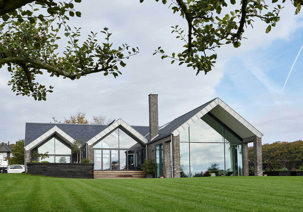Idées déco pour une grande façade de maison marron en verre de plain-pied avec un toit à croupette.