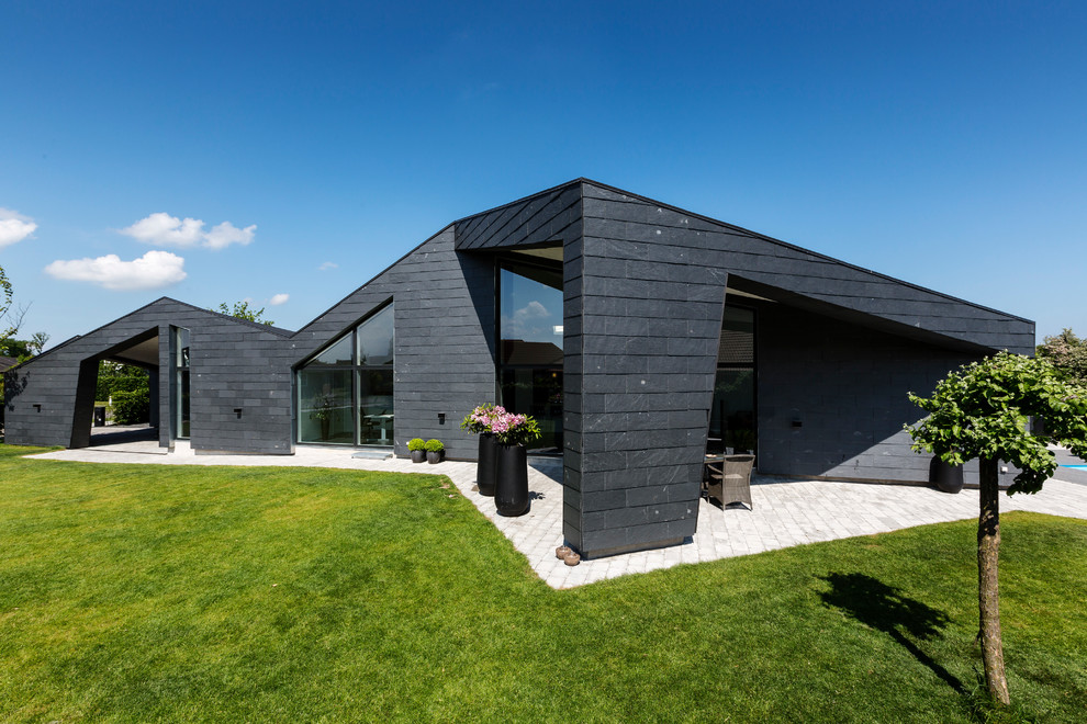Ejemplo de fachada negra actual grande de una planta con revestimiento de ladrillo y tejado a la holandesa