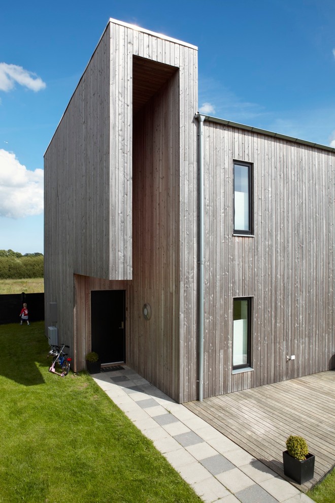 Photo of a brown contemporary house exterior in Copenhagen with wood cladding and a flat roof.