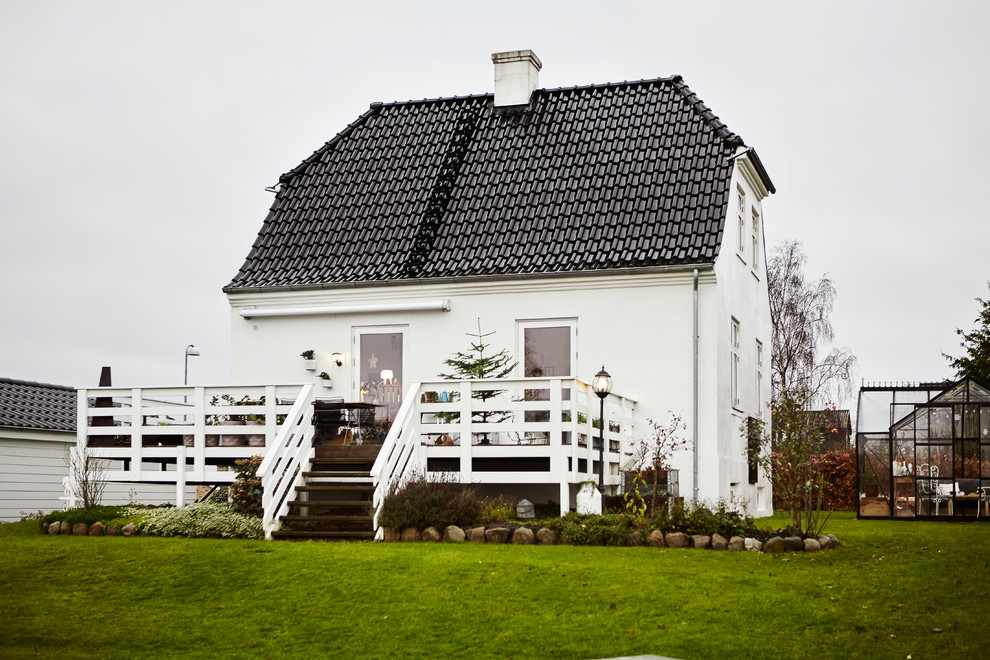 Пример оригинального дизайна: двухэтажный, белый дом в скандинавском стиле с мансардной крышей и черепичной крышей