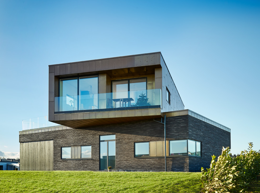 This is an example of a brown and large contemporary two floor house exterior in Aalborg with a flat roof and concrete fibreboard cladding.