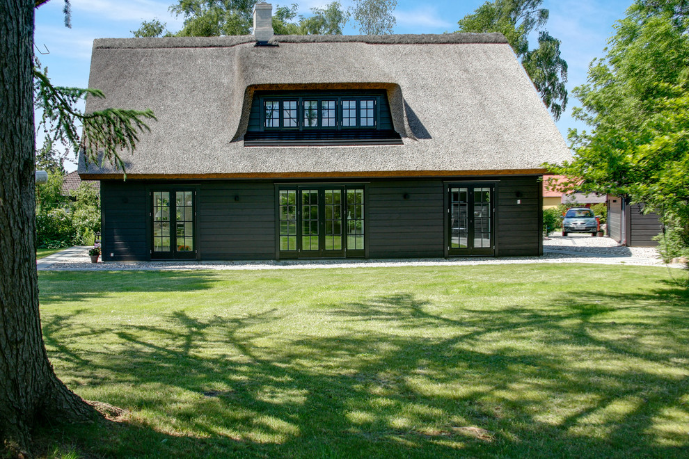 Diseño de fachada negra de estilo de casa de campo grande de dos plantas con revestimiento de madera y tejado a la holandesa