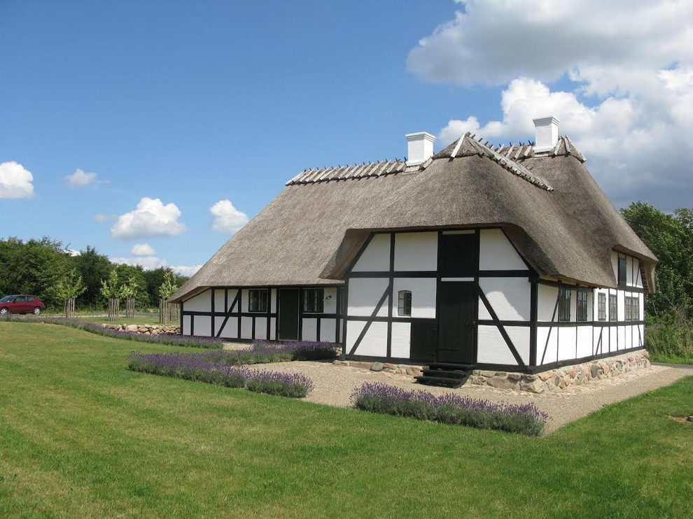 Foto de fachada blanca nórdica de tamaño medio de dos plantas con revestimiento de adobe y tejado a cuatro aguas
