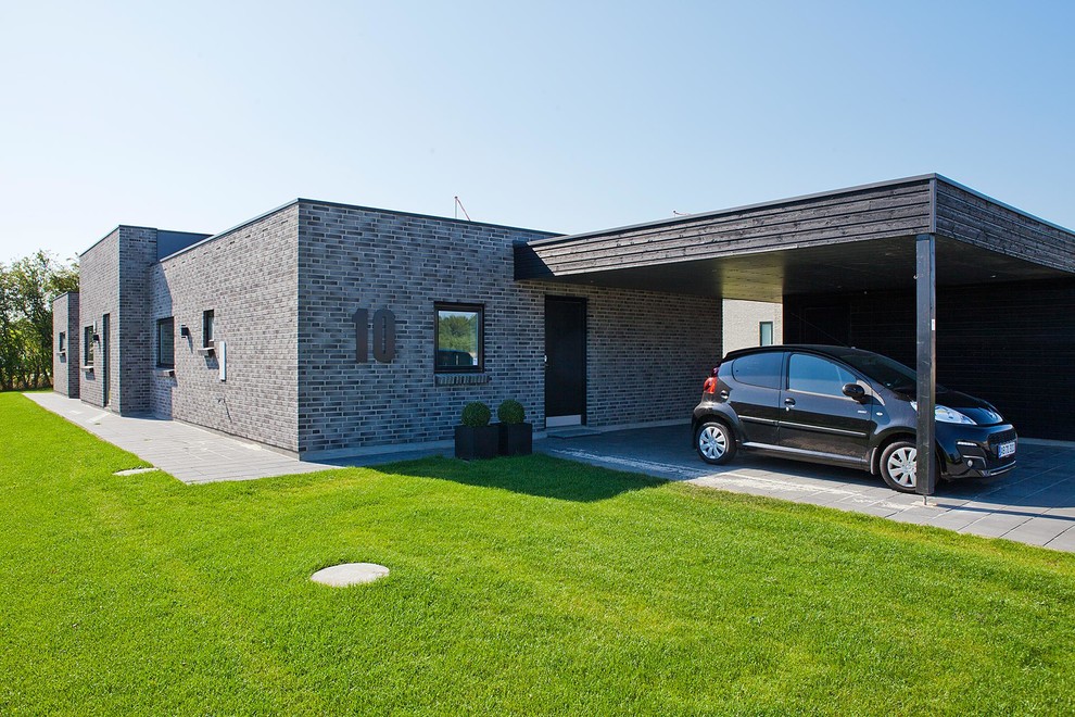 Cette photo montre une façade de maison grise tendance en brique de plain-pied avec un toit plat.