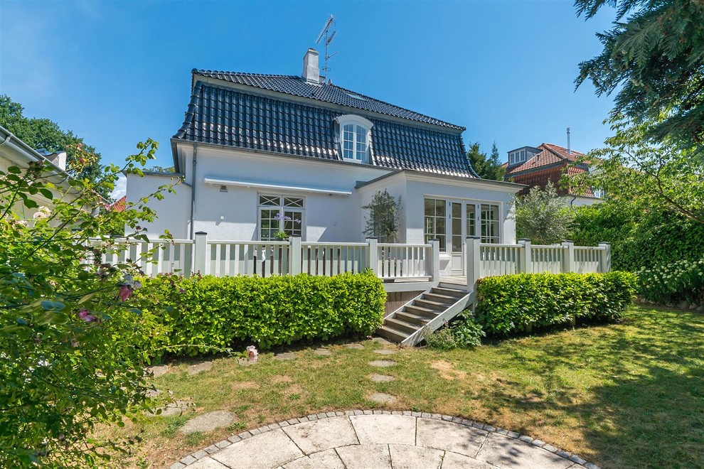 This is an example of a white scandi two floor detached house in Other with a hip roof and a tiled roof.