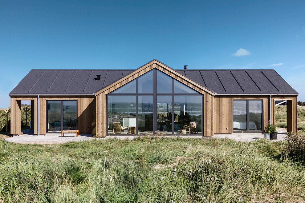 Идея дизайна: одноэтажный, деревянный, коричневый частный загородный дом среднего размера в скандинавском стиле с двускатной крышей и крышей из смешанных материалов