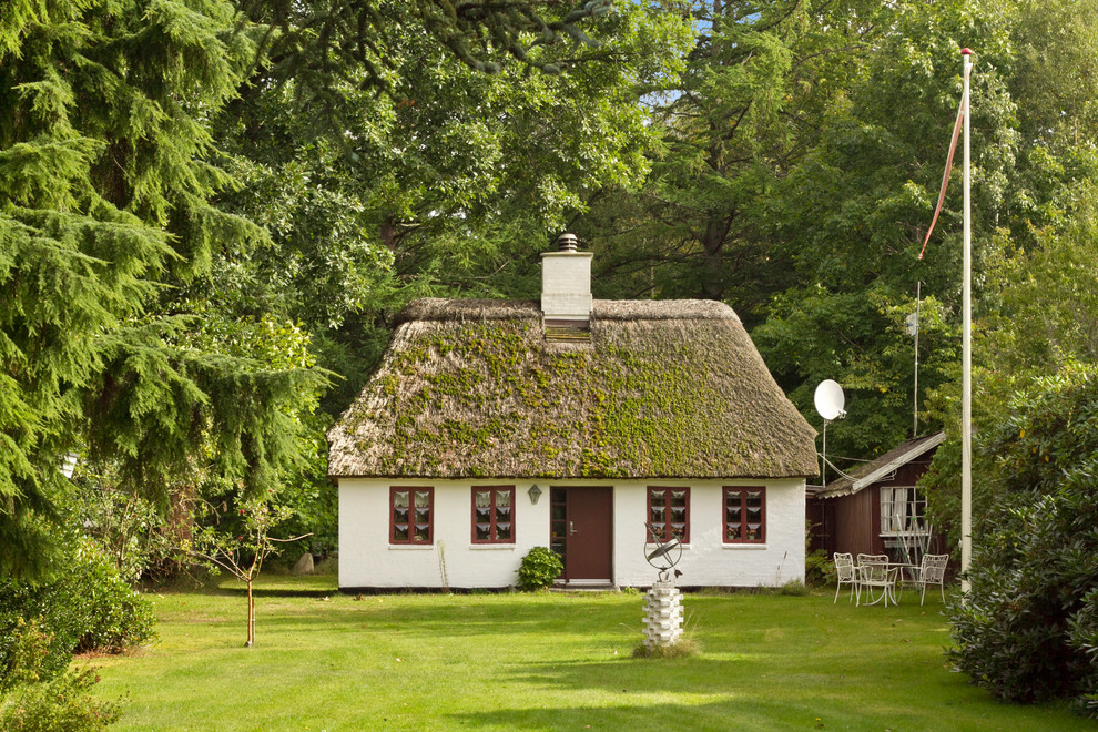 This is an example of a white and medium sized scandinavian bungalow brick house exterior in Aarhus with a pitched roof.