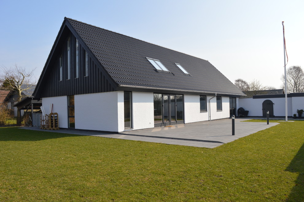 На фото: двухэтажный, белый дом среднего размера в скандинавском стиле с облицовкой из цементной штукатурки и вальмовой крышей