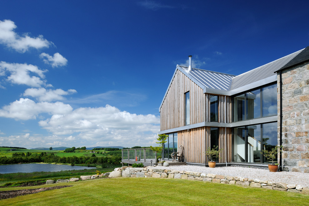 На фото: двухэтажный, серый частный загородный дом среднего размера в скандинавском стиле с комбинированной облицовкой и металлической крышей с