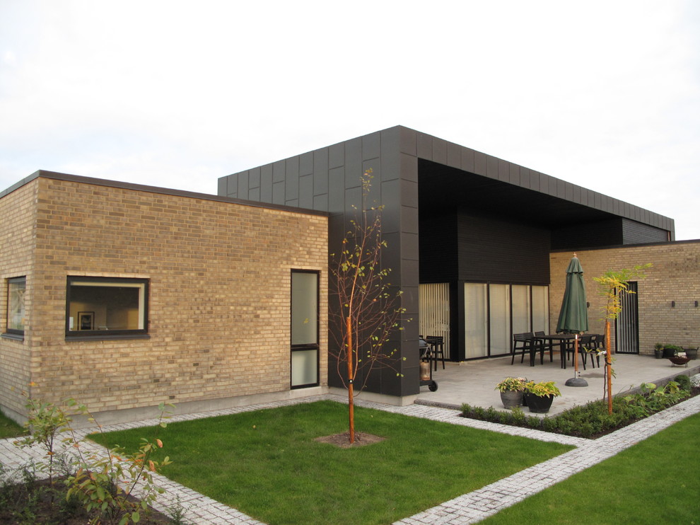 Diseño de fachada multicolor moderna de tamaño medio con revestimiento de ladrillo y tejado plano