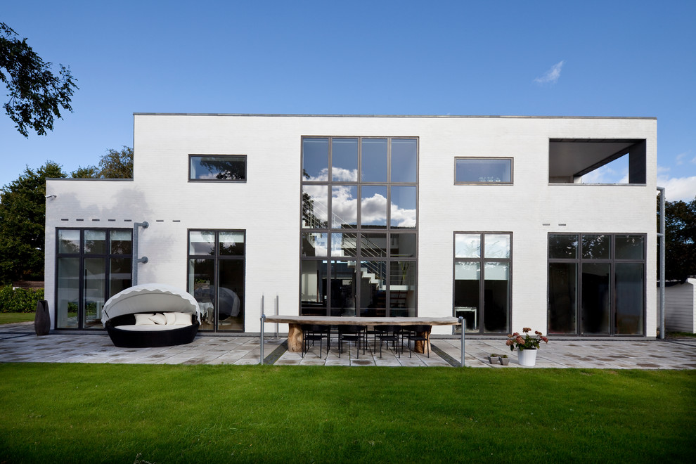 Diseño de fachada blanca nórdica grande de dos plantas con revestimiento de ladrillo y tejado plano