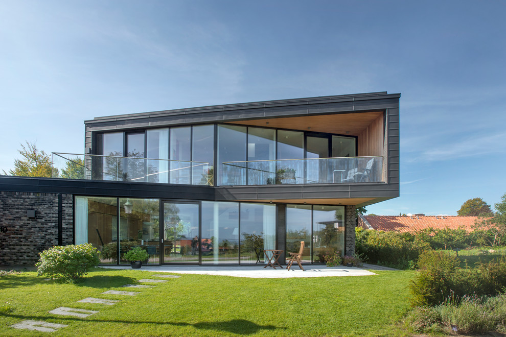 Diseño de fachada negra moderna grande de dos plantas con revestimiento de vidrio y tejado plano