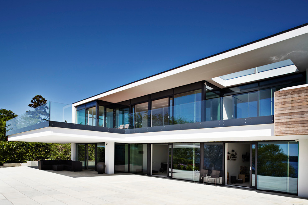 Imagen de fachada blanca escandinava grande de dos plantas con revestimiento de vidrio y tejado plano