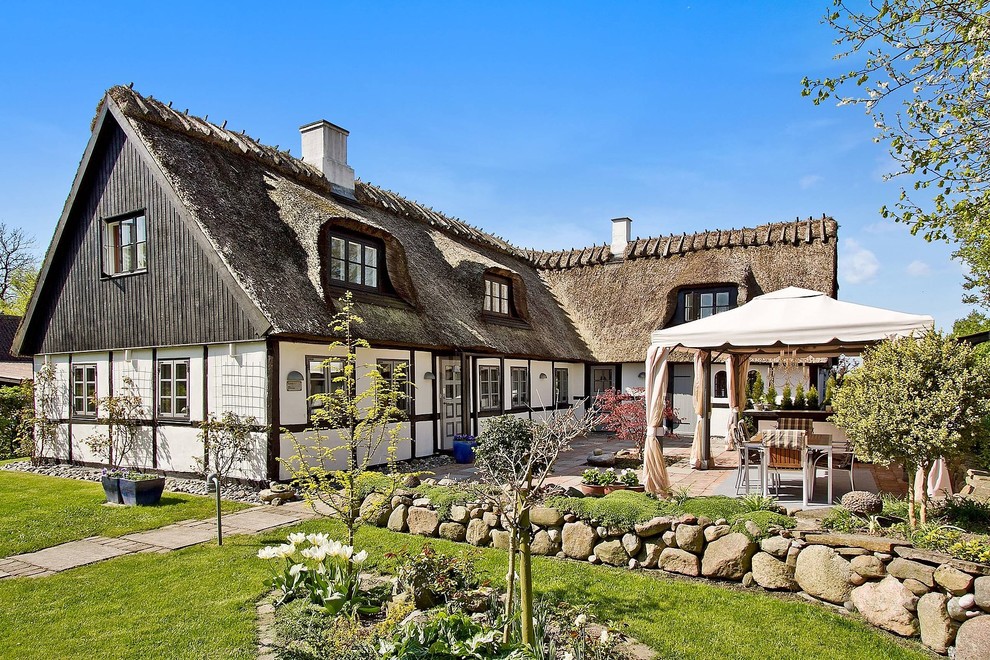 Modelo de fachada blanca de estilo de casa de campo de tamaño medio de dos plantas con revestimiento de ladrillo y tejado a la holandesa