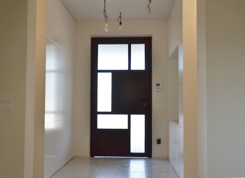Idee per un ampio ingresso con pareti bianche, pavimento in cemento, una porta singola, una porta in metallo e pavimento bianco