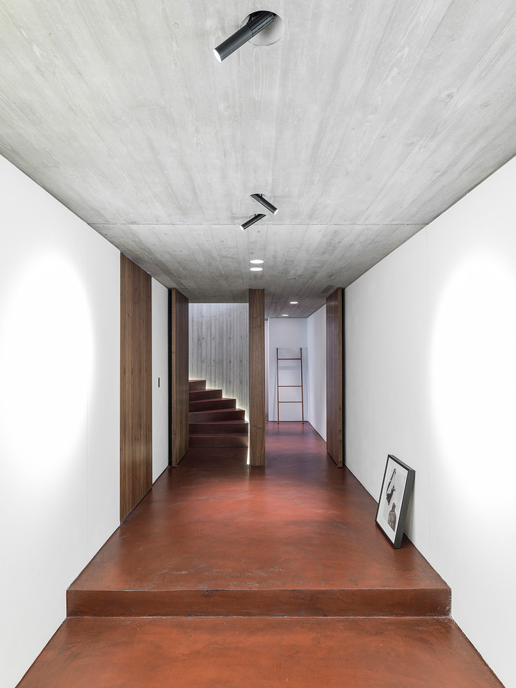 Cette image montre un grand couloir design avec sol en béton ciré et un sol rouge.
