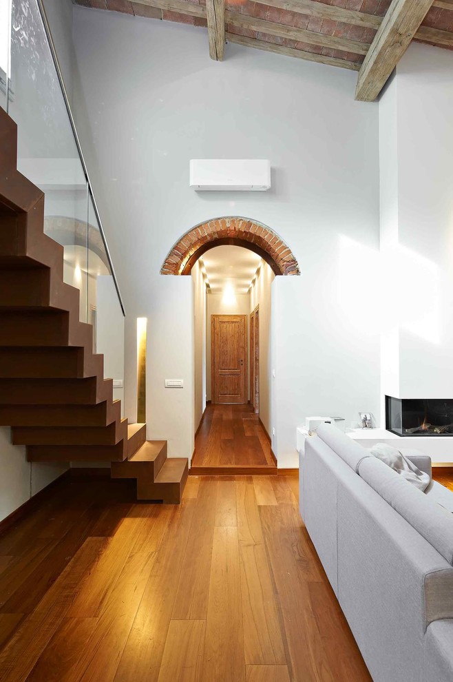 Diseño de recibidores y pasillos mediterráneos con paredes blancas, suelo de madera en tonos medios y iluminación