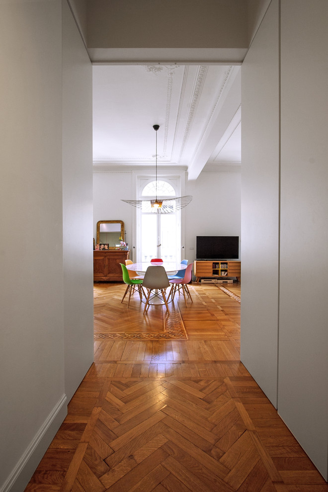 Immagine di un ingresso minimalista di medie dimensioni con pareti bianche, pavimento in legno massello medio, una porta a pivot, una porta bianca e pavimento marrone