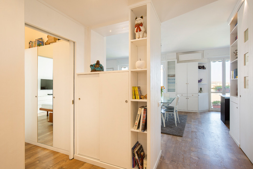 Foto de distribuidor actual de tamaño medio con paredes blancas, suelo de madera clara, puerta simple y puerta blanca