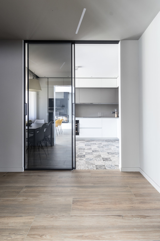 Immagine di un grande ingresso minimalista con pareti grigie, pavimento con piastrelle in ceramica, una porta singola, una porta grigia e pavimento marrone