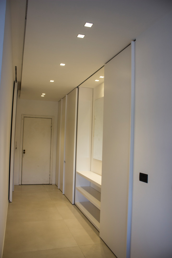 На фото: фойе среднего размера в современном стиле с белыми стенами, полом из керамической плитки, раздвижной входной дверью и белой входной дверью