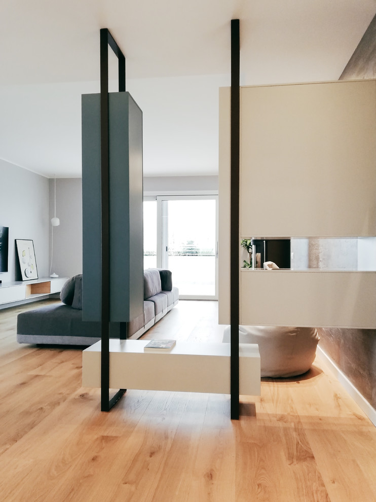 This is an example of a large contemporary foyer in Milan with grey walls and light hardwood flooring.