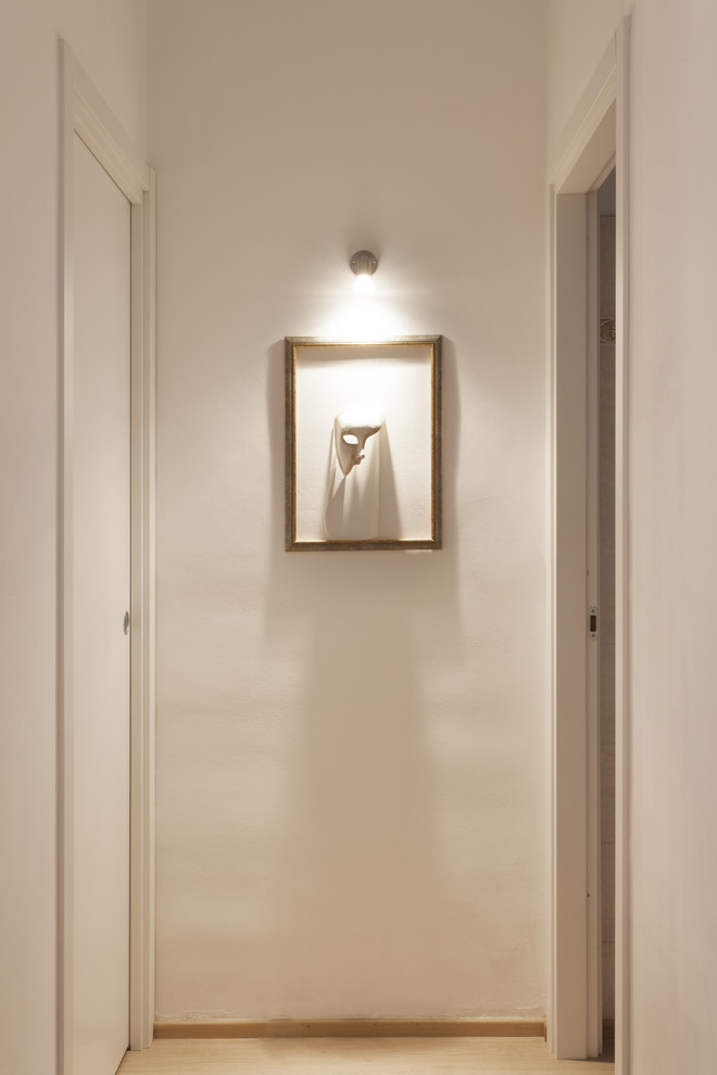 Réalisation d'un petit couloir design avec un mur blanc et un sol en bois brun.