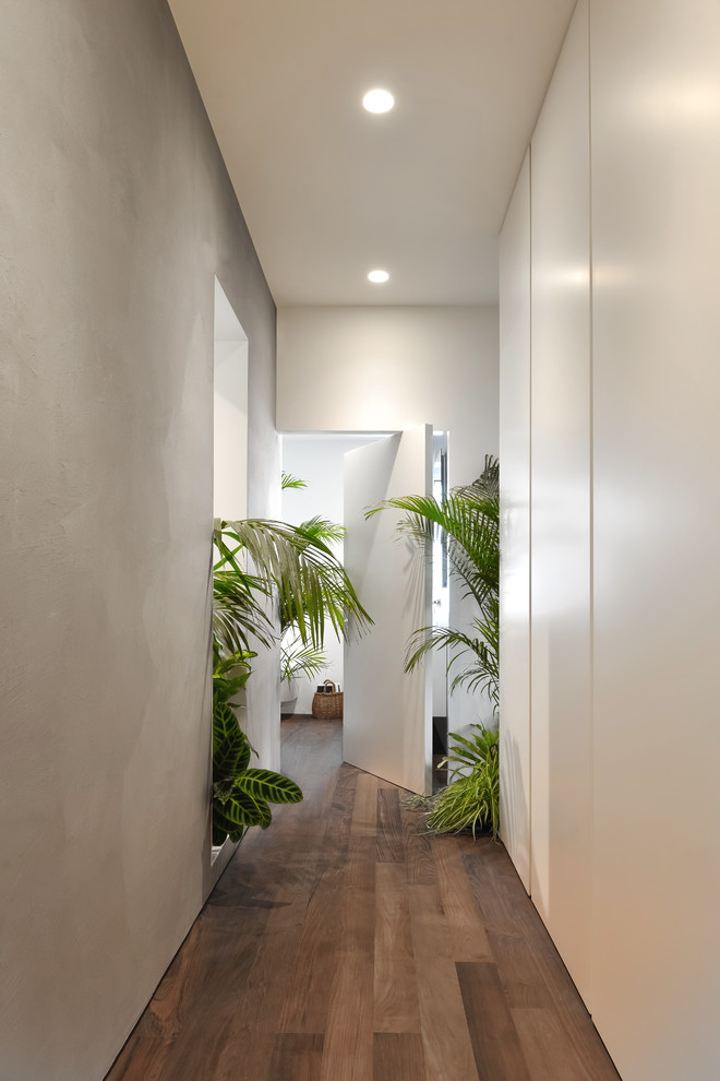 Aménagement d'un couloir exotique de taille moyenne avec un mur gris et un sol en bois brun.