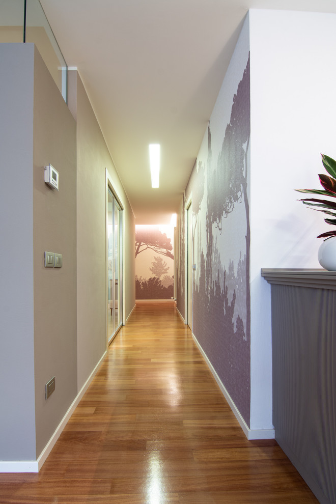На фото: большой коридор в современном стиле с бежевыми стенами, деревянным полом, коричневым полом и обоями на стенах с