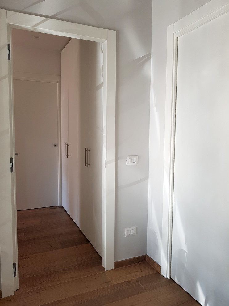 Cette photo montre un petit couloir tendance avec un mur blanc, un sol en carrelage de porcelaine et un sol marron.
