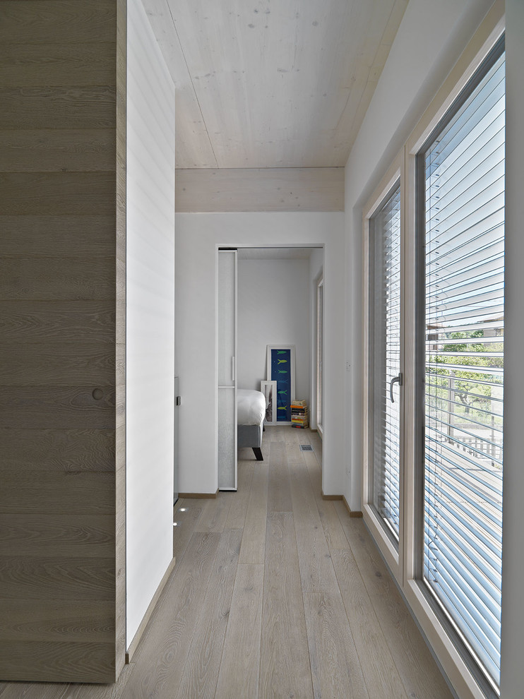 Immagine di un ingresso o corridoio contemporaneo di medie dimensioni con pareti bianche e pavimento in legno massello medio