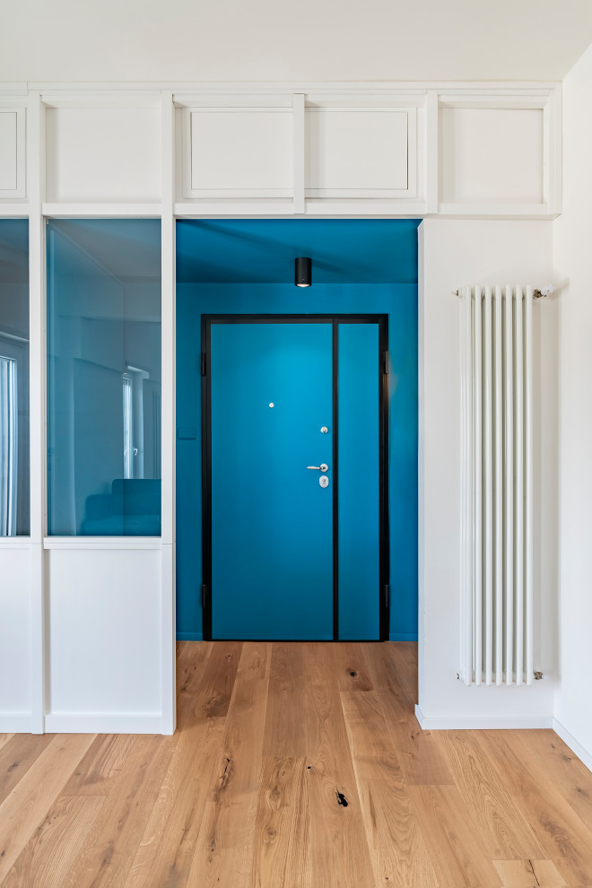 Imagen de vestíbulo nórdico pequeño con paredes azules, suelo de madera clara, puerta simple, puerta azul y bandeja