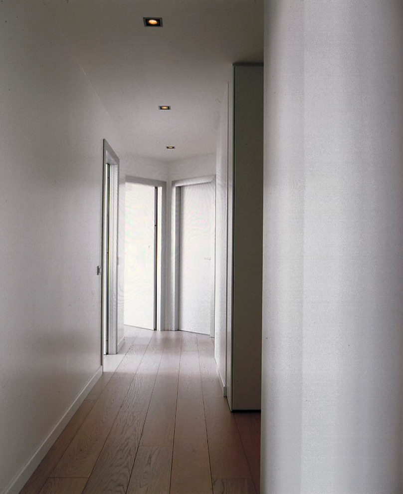 Идея дизайна: огромный коридор в стиле модернизм с белыми стенами, светлым паркетным полом и белым полом