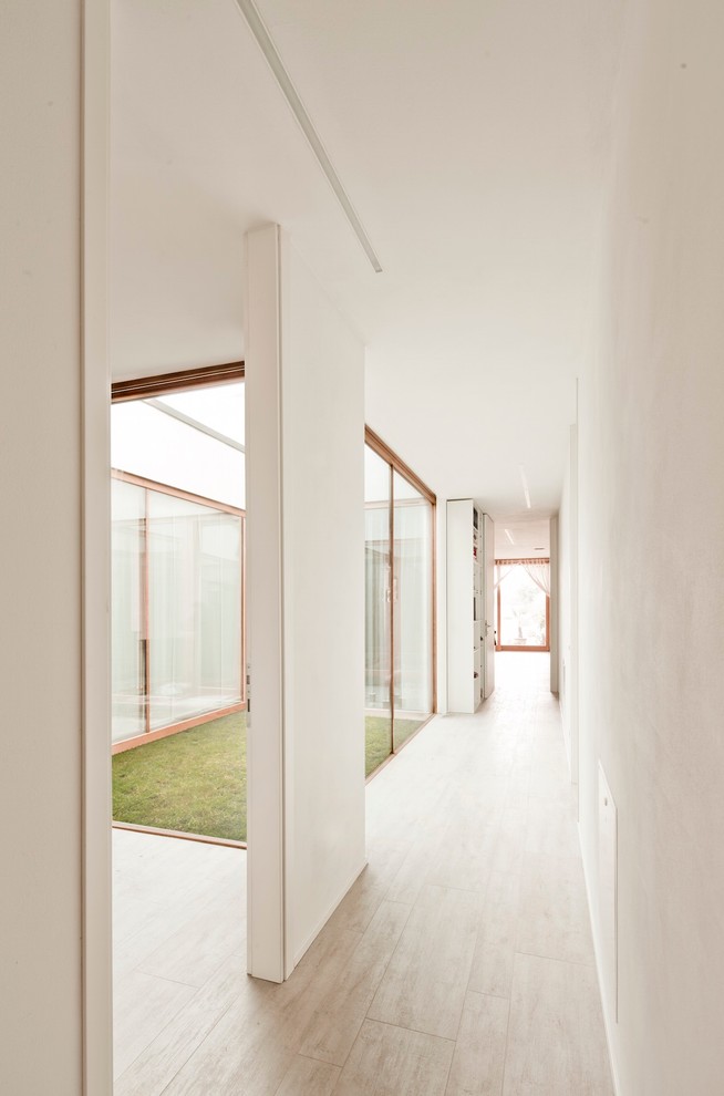 Esempio di un grande ingresso o corridoio minimal con pareti bianche e pavimento in legno verniciato