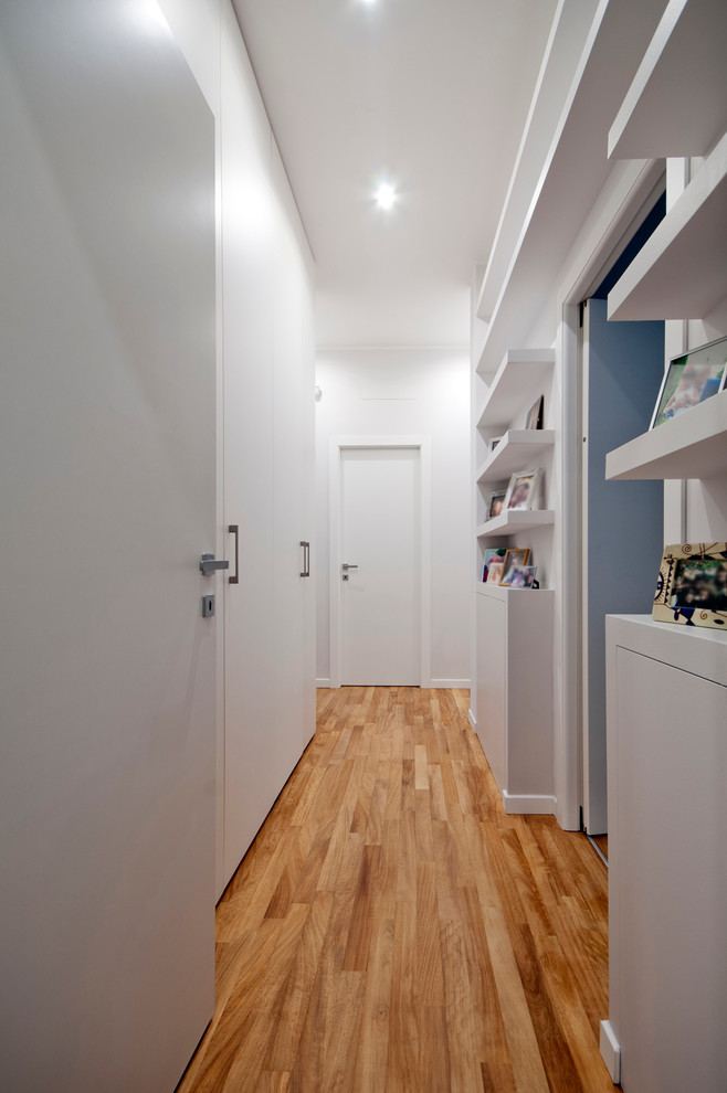 На фото: коридор: освещение в современном стиле с белыми стенами и паркетным полом среднего тона с