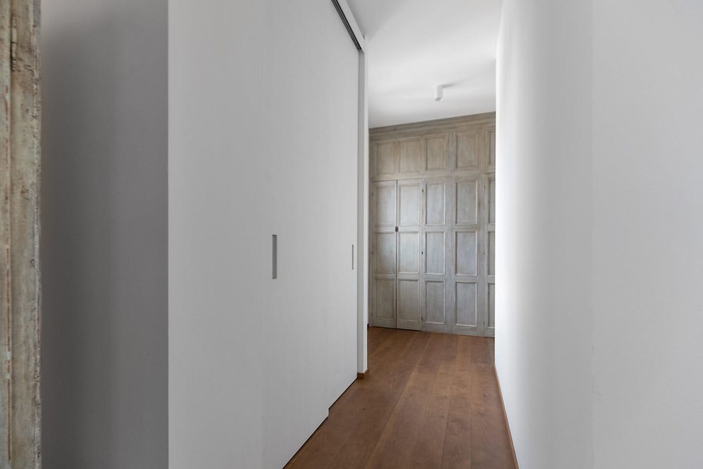 Cette photo montre un couloir tendance de taille moyenne avec un mur blanc, parquet peint et un sol marron.