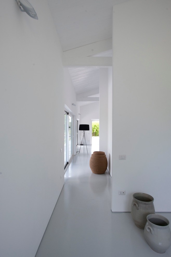 На фото: коридор в стиле модернизм с белыми стенами, бетонным полом и белым полом с