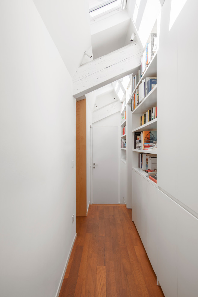 Idée de décoration pour un petit couloir design avec un mur blanc, poutres apparentes, un plafond voûté, un sol en bois brun et un sol marron.